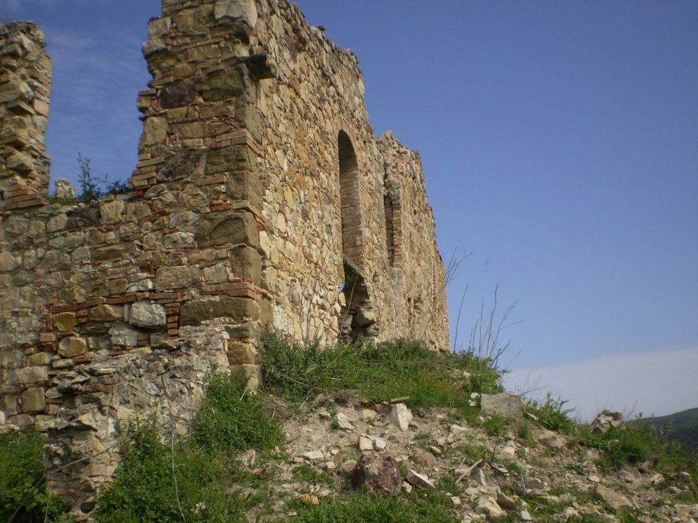 Vista dal basso dell'angolo in pietra e delle aperture ad arco del rudere